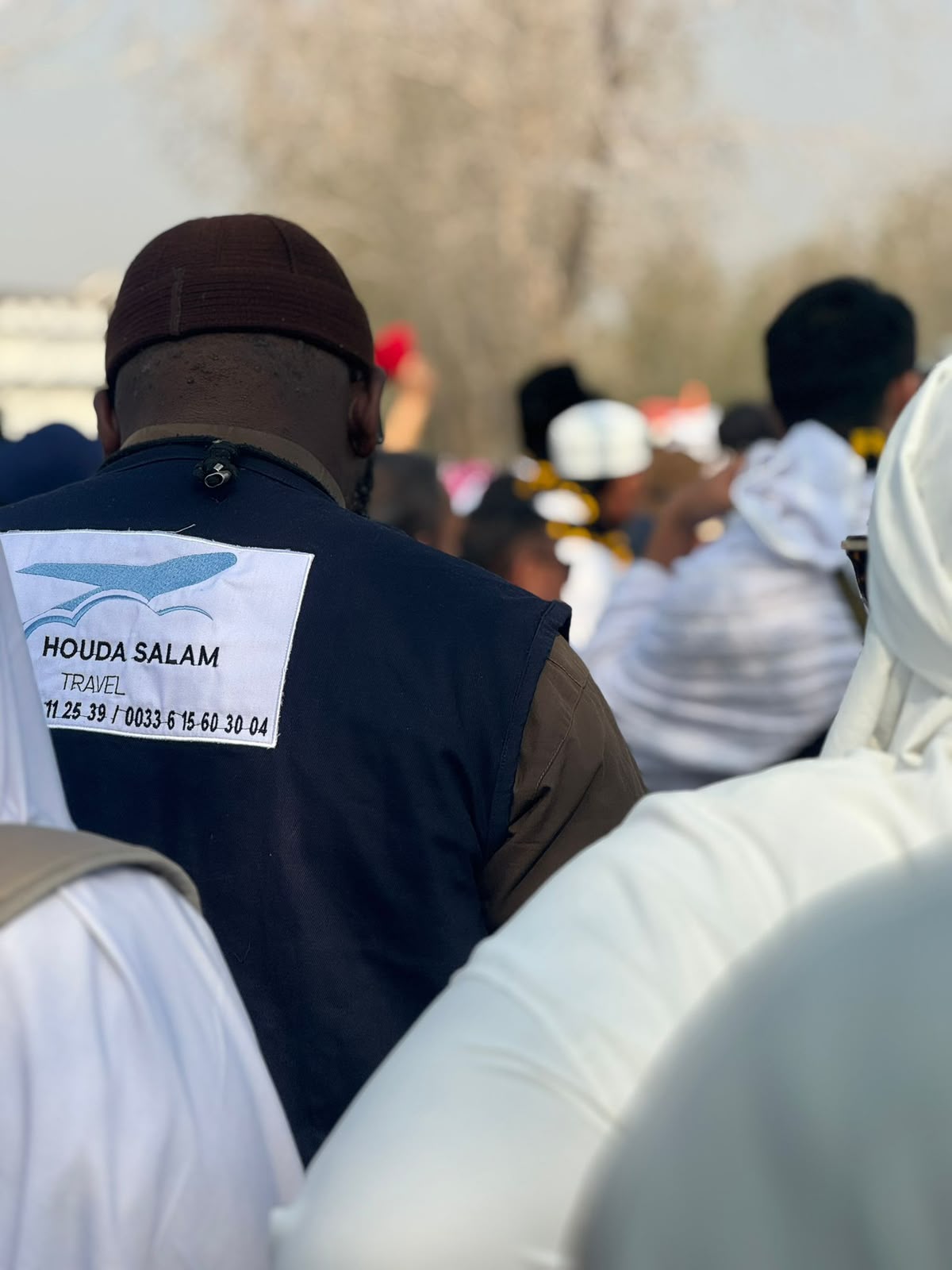 Accompagnateur Houda Salam Travel en gilet floqué, au milieu d'un groupe de pèlerins